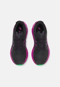 Zapatillas de correr negras con acentos morados, tela texturizada y detalles verdes en la suela. Cuentan con cordones estándar y un interior acolchado.