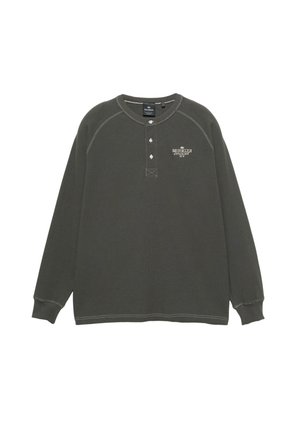 Donkergroene katoenen Henley-trui met lange mouwen, geribbelde textuur, drieknopenbies en witte stikseldetails.