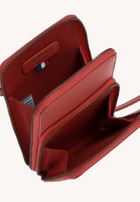 Portefeuille en cuir rouge avec fermeture éclair, présentant plusieurs compartiments, une finition texturée et un petit accent de drapeau à l'intérieur.