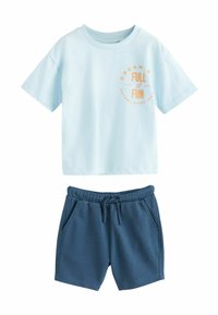 Ljusblå bomulls-T-shirt med orange grafisk text "DRÖM STORT FULL AV NÖJE," i kombination med marinblå bomullsshorts med elastisk midja.