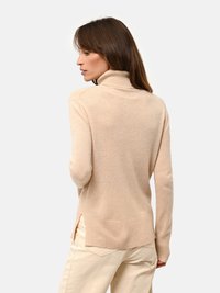 Maglione beige a collo alto in morbido tessuto lavorato a maglia, con orlo a coste e spacchetti laterali per un fit rilassato. Progettato con maniche lunghe.
