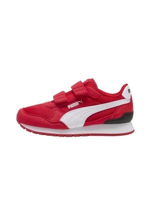 Zapatilla Puma roja con una franja blanca, dos tiras de velcro, detalle negro en el talón y suela blanca, vista lateral sobre un fondo blanco.