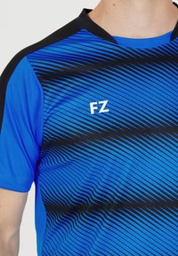Blå idrottströja med diagonala svarta ränder, med svart krage och vitt "FZ"-logotyp på sidan. Tillverkad av lättviktsmaterial.