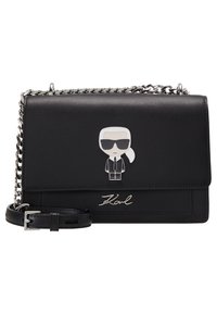 Borsa a tracolla in pelle nera con una catenina in argento, con un personaggio dei cartoni animati sul davanti e un logo impresso sul fondo.