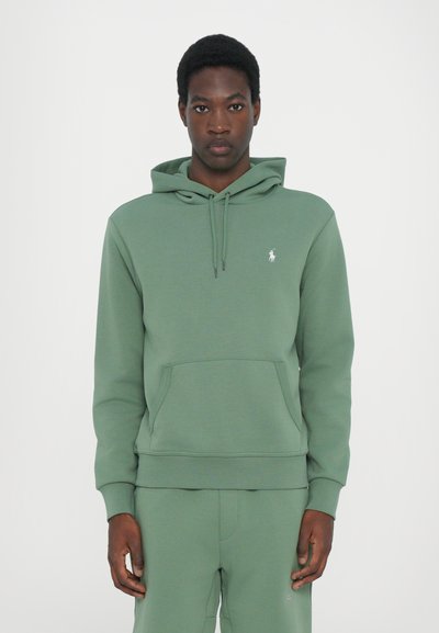 Groene katoenen hoodie met een kangoeroezak, verstelbare trekkoordkap en een klein geborduurd logo op de borst. Zachte textuur.