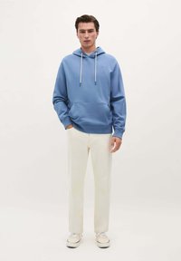 Lichtblauwe hoodie met een trekkoord, voorzak en geribbelde mouwen, gecombineerd met witte broek en casual sneakers. Zacht, glad materiaal.