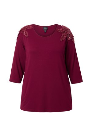 Burgundy ¾ sleeve top in soft fabric featuring ornate beaded floral accents on shoulders and a round neckline.