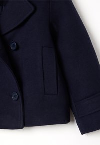 Manteau en mélange de laine bleu marine avec un design à double boutonnage, de grands revers, deux boutons et une poche latérale au toucher doux.