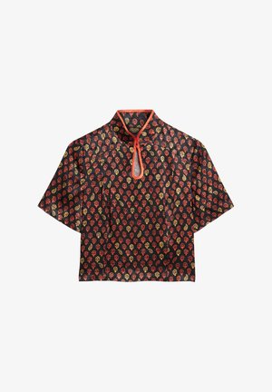 Kortærmet bluse i sort stof med et rødt og guld blomster mønster. Bemærkelsesværdig nøglehuludskæring med en kontrasterende rød kant.