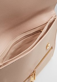 Pink synthetic leather bag interior with a smooth texture; features a zippered pocket and a gold-tone zipper accent.