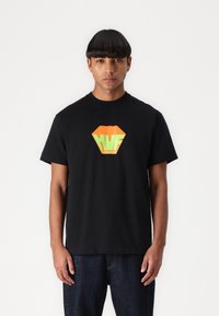 Zwart katoenen t-shirt met een levendig oranje en groene ruitvormige logo op de borst. Korte mouwen, ronde hals, ontspannen pasvorm.