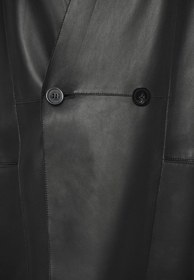 Melns ādas žakete ar dubultpogas dizainu, divām melnām pogām, gludu tekstūru un piemērotiem šuvumiem bez redzamām rakstu zīmēm.