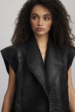 Vesta fără mâneci din piele neagră, cu guler lat și ascuțit, închidere cu fermoar vizibil și detalii texturate pe suprafață.