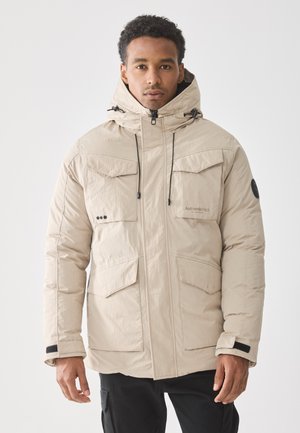 Chaqueta acolchada beige con capucha, que cuenta con varios bolsillos frontales, cordones ajustables y un acabado liso y mate.