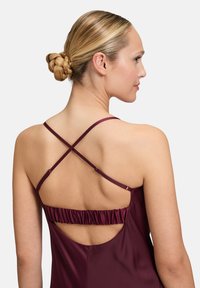 Abito borgogna senza schienale con spalline incrociate e dettagli arricciati in vita. Tessuto liscio con una silhouette elegante e design con schiena aperta.