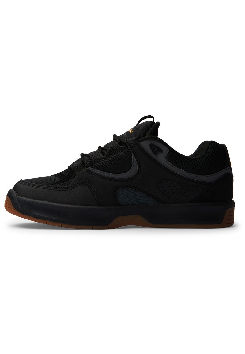 Black athletic shoes with mesh and suede materials, featuring lace-up design, a cushioned sole, and a gum rubber outsole. Subtle branding accents.