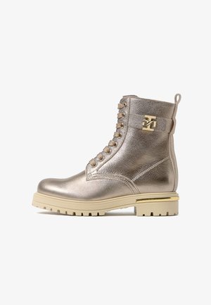 Metallic gold ankle boot with a textured finish, round toe, lace-up front, gold hardware accent, and chunky beige sole.