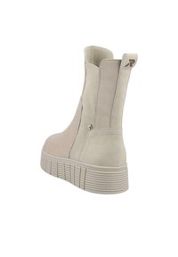 Botas altas beige con un exterior de gamuza suave, paneles laterales elásticos acanalados y una suela de goma texturizada para mayor agarre.
