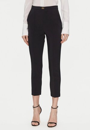 Pantaloni neri con un taglio sartoriale, vita alta, lunghezza cropped e un accento dorato con logo in vita. Tessuto morbido e design classico.