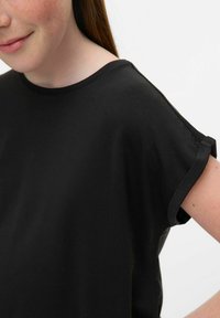 T-shirt noir à manches courtes fabriqué en tissu doux, avec un col rond et des manches retroussées, ayant une texture lisse et une coupe décontractée.