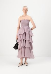 Strapless, tiered lavendelkjole med flæser, lavet af letvægtsstof. Har en smocked korsette og en flydende silhuet.