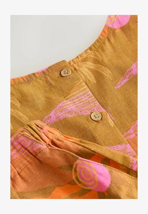 Brauner Stoff mit abstraktem Blumenmuster in Pink und Orange, versehen mit zwei kleinen runden Holzknöpfen und gerafften Nähten im unteren Bereich.