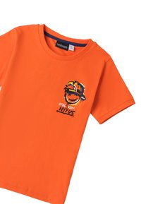Camiseta de algodón naranja con cuello redondo, mangas cortas y un diseño impreso que presenta a un personaje sonriente con una gorra y texto abajo.