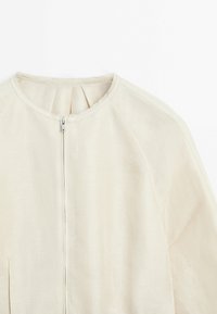 Crème-kleurige linnen blazer met ronde halslijn en een voorzakluiting, met details van de bovenste voorkant en schouders.