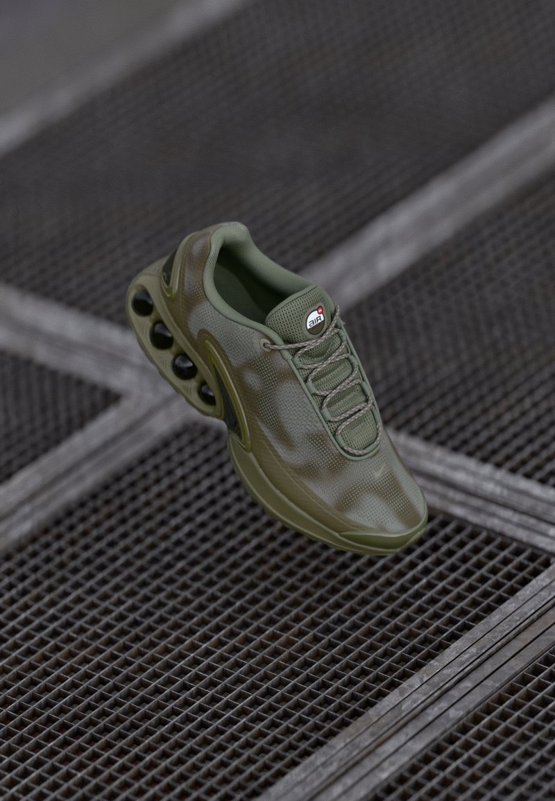 Green athletic shoe with a textured mesh upper, lacing system, and distinctive air cushioning pods along the sole.