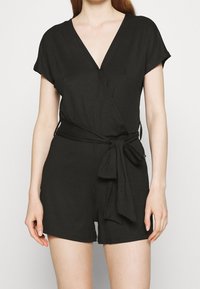 Czarny kombinezon z prążkowanej tkaniny, z krótkimi rękawami, dekoltem w kształcie litery V, wiązanym w talii oraz krótkimi nogawkami, charakteryzujący się delikatną fakturą.