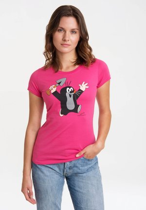 Pink cotton t-shirt featuring a cartoon mole holding a small shovel, with short sleeves and a fitted design, paired with light blue jeans.