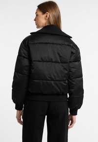 Zwarte pufferjack met een cropped ontwerp, rib gebreide manchetten en een brede kraag. Glad, glanzend materiaal met horizontale stiksels.