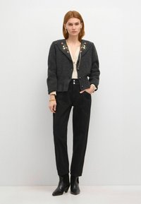 Graue Wolljacke mit floraler Stickerei auf den Schultern, cremige Bluse, schwarze hoch geschnittene Hose und schwarze Knöchelstiefel. Sauberes, strukturiertes Design.