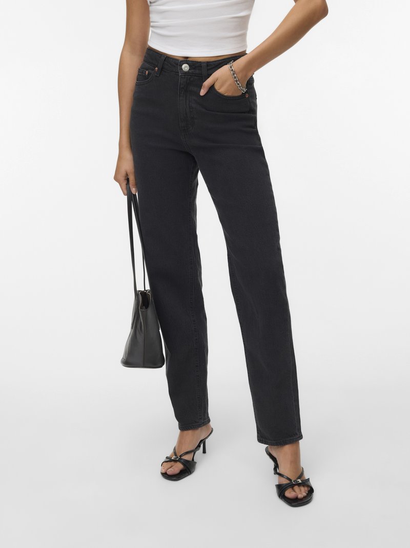 Fekete, magas derekú, egyenes szárú farmernadrág, gombos rögzítéssel, elülső zsebekkel és letisztult dizájnnal. Fekete, magas sarkú szandállal párosítva.