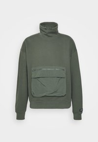 Sudadera verde oliva con cuello alto, corte holgado y un gran bolsillo delantero con cremallera. Puños y dobladillo acanalados con un acabado texturizado.