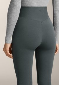 Kalhoty s vysokým pasem v tmavě šedé barvě, ribbovaného designu, s hladkou texturou a minimalistickým vzhledem. Těsně přiléhající s pevným pasem.