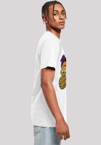 White cotton t-shirt featuring colorful cartoon graphic on the front. Short sleeves, crew neck, relaxed fit. Worn with light blue jeans.