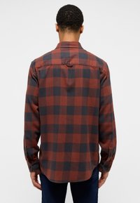 Rød og marineblå ternet flannel skjorte, lange ærmer, knaplukning i håndleddene, buet nederkant, med en ensfarvet ryg og krave, lavet af blødt stof.