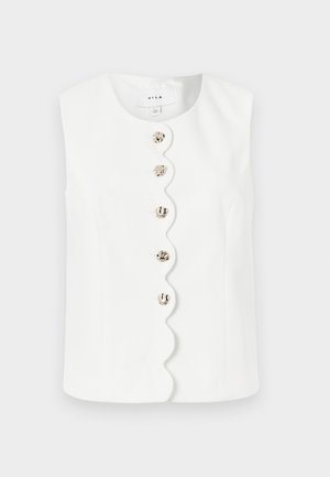 Witte mouwloze top met afgeschuinde voorkant en vijf onregelmatige metalen knopen over het midden.