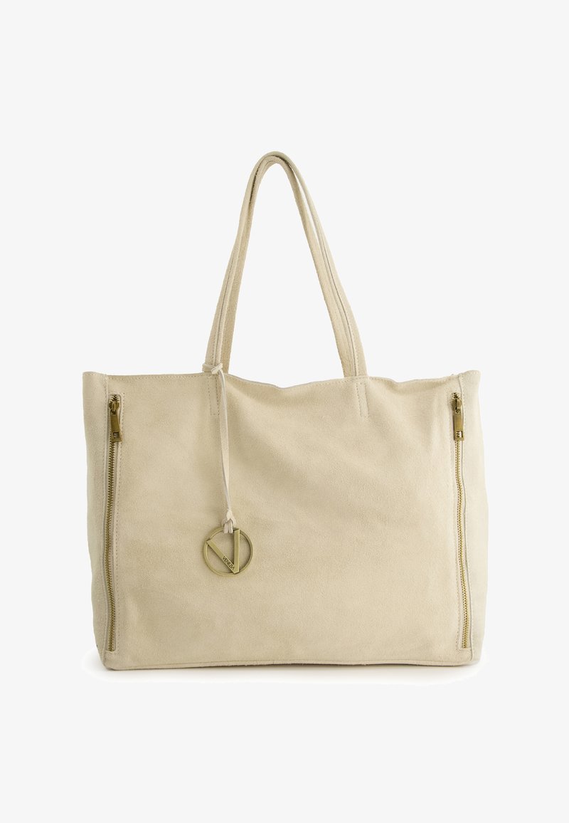 Beige suede tote bag with two zippered sides, flat design, long handles, and a round gold accent detail attached to a drawstring.