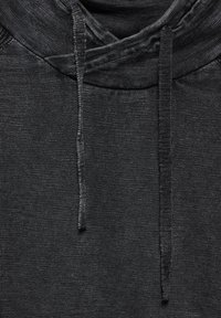 Jersey negro con un tejido texturizado, que cuenta con capucha, cordones y un diseño relajado. Sin logotipos ni patrones adicionales visibles.