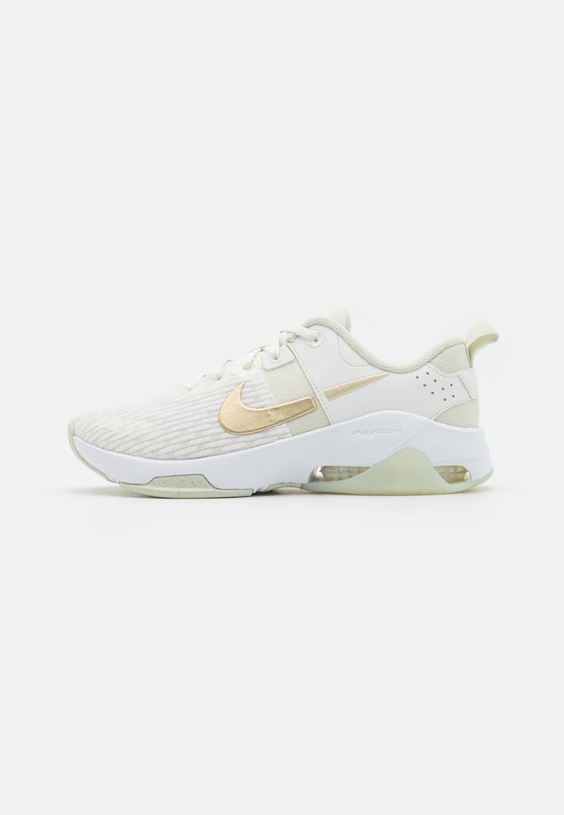 White Nike sneakers with a gold swoosh. The design features a textured upper, padded collar, and a translucent sole with air cushioning.