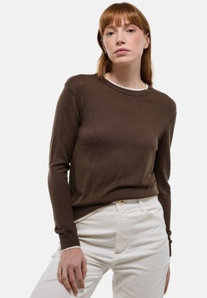 Pull en tricot marron avec un col rond, des manches longues et des poignets côtelés, assorti à un pantalon en velours côtelé blanc. Design simple et classique.