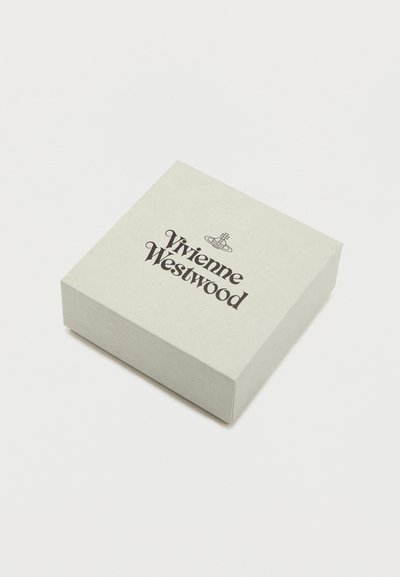 Τετράγωνο μπεζ κουτί Vivienne Westwood με μαύρο λογότυπο και έμβλημα σε λευκή επιφάνεια.