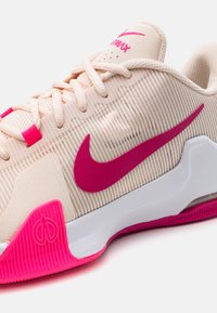 Nike Air Max sneaker; crème bovenwerk van stof met roze accenten, gestructureerde strepen, witte tussenzool, roze buitenzool en logodetailing.