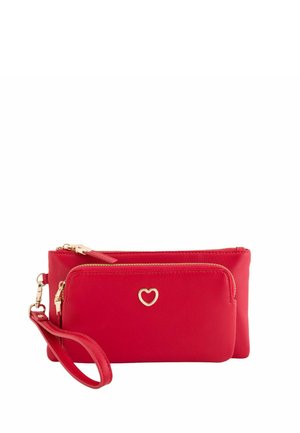 Portefeuille-pochette rouge texturé avec deux compartiments zippés et un charm en forme de cœur doré sur la poche avant.