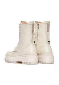 Bottes de combat en cuir blanc avec une finition texturée, dotées d'un laçage à l'avant, d'une fermeture éclair sur le côté et d'une semelle en caoutchouc épaisse.