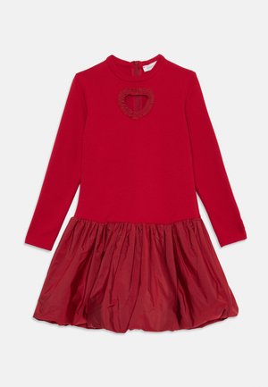 Vestido vermelho de manga longa com decote redondo, recorte em forma de coração com babados no peito e saia texturizada com franzidos.