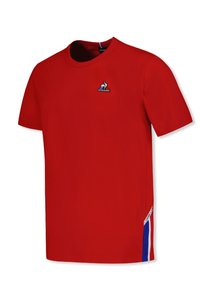 T-shirt en coton rouge avec un col rond, des manches courtes et un petit logo brodé sur la poitrine. Présente des accents rayés blancs et bleus sur les côtés.