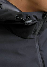 Zwarte hooded jacket met een gladde, waterafstotende buitenkant, verstelbare trekkoordsluiting en een volle lengte rits aan de voorkant.